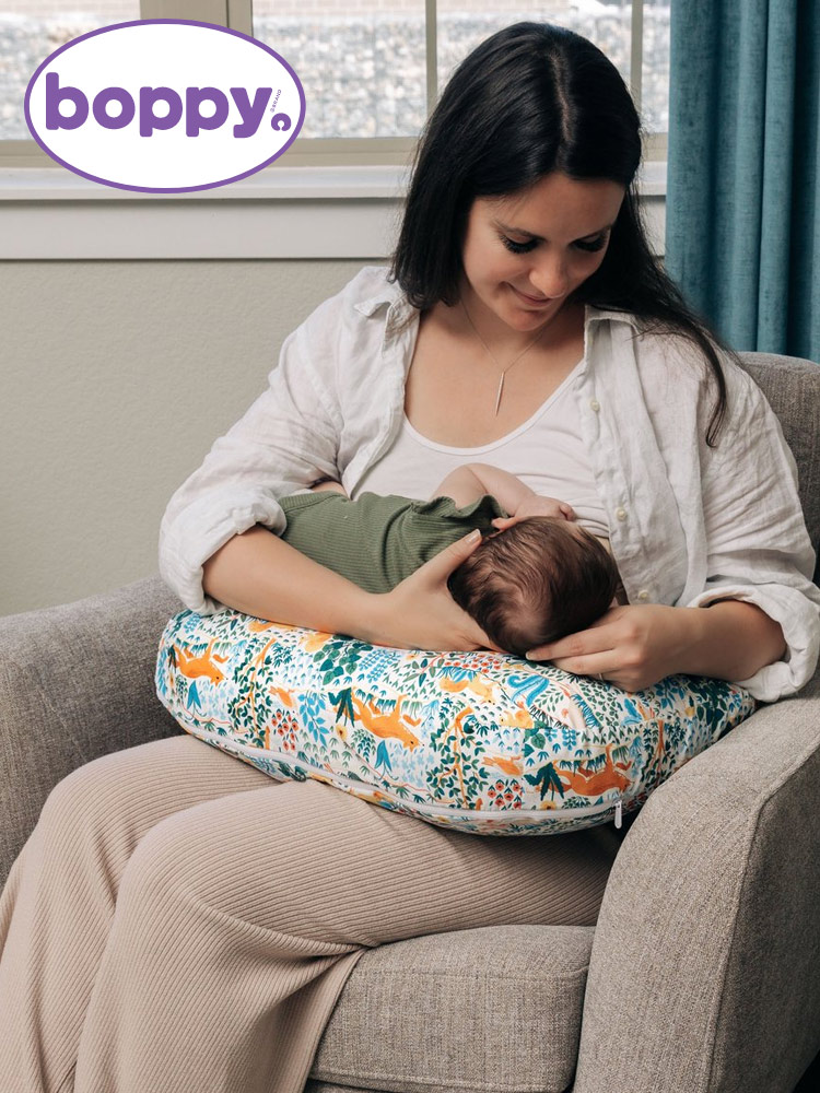 a woman breastfeeding a baby on the Boppy Nursing Pillow