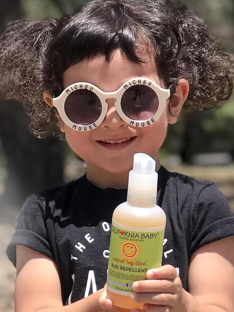 a child holding a spray bottle of california baby natural bug repellent a child holding a spray bottle of California baby natural bug repellent