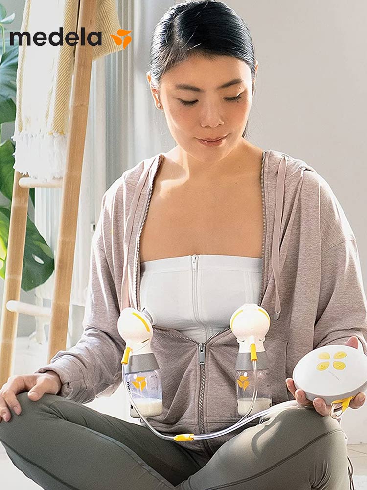 woman sitting on floor using the medela swing maxi breast pump