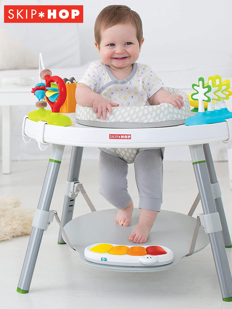 a smiling baby sitting in the skip hop explore and more activity center